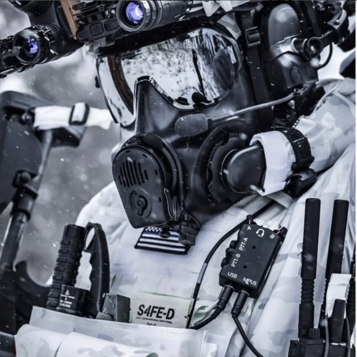Alpine special-operations operator in white winter camouflage with full Avon Protection CBRN gas mask, NVGs, and an S4FE-D® D.I.R.T. wipe pouch mounted on the plate carrier — featured by Avon Protection on their official channels.