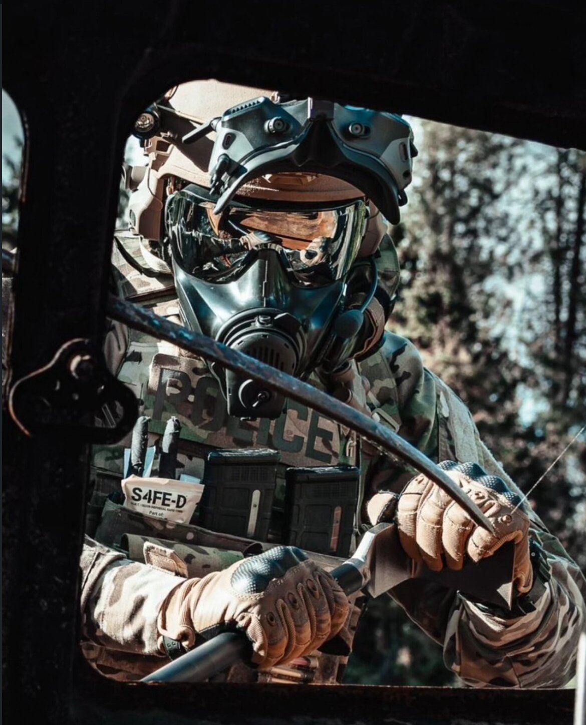 Police tactical operator in MultiCam with a POLICE-marked plate carrier, full CBRN gas mask, helmet with NVG mount, and an S4FE-D Mil Spec wipe pouch mounted on the chest rig — posted by @s4fe_d