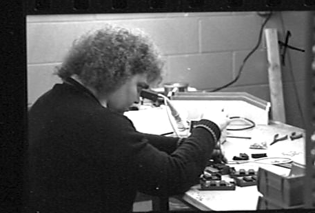 LTI bench technician at a soldering station building electronic modules, c. 1986