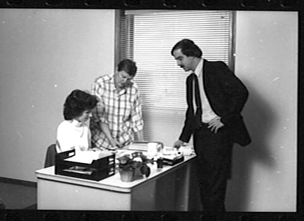 LTI office team discussing work at a desk, c. 1986